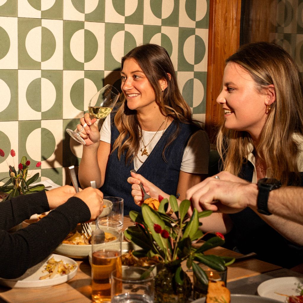 Two friends laughing and drinking wine over dinner