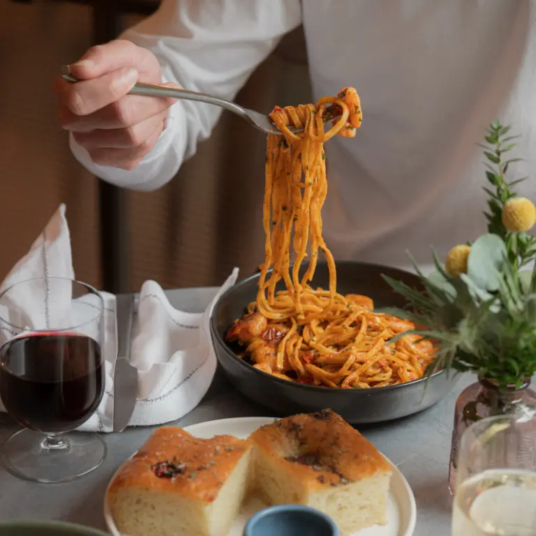 prawn linguine hanging from fork held by man