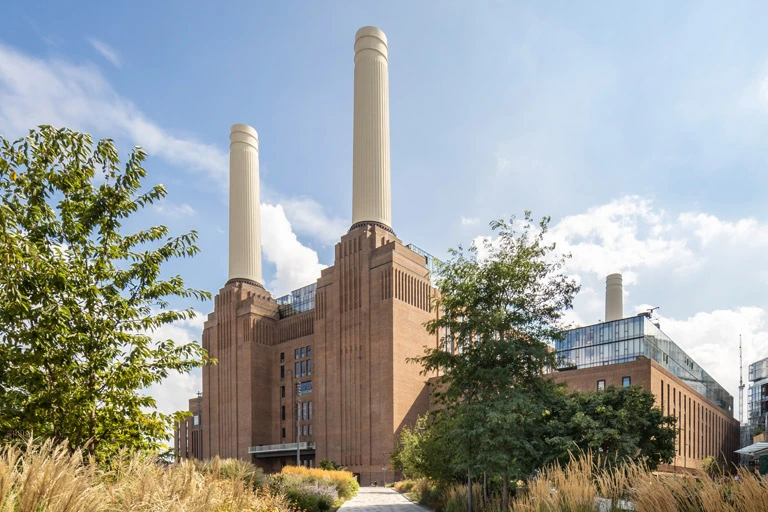 Exterior photo of Battersea Powerstation with trees and long grass